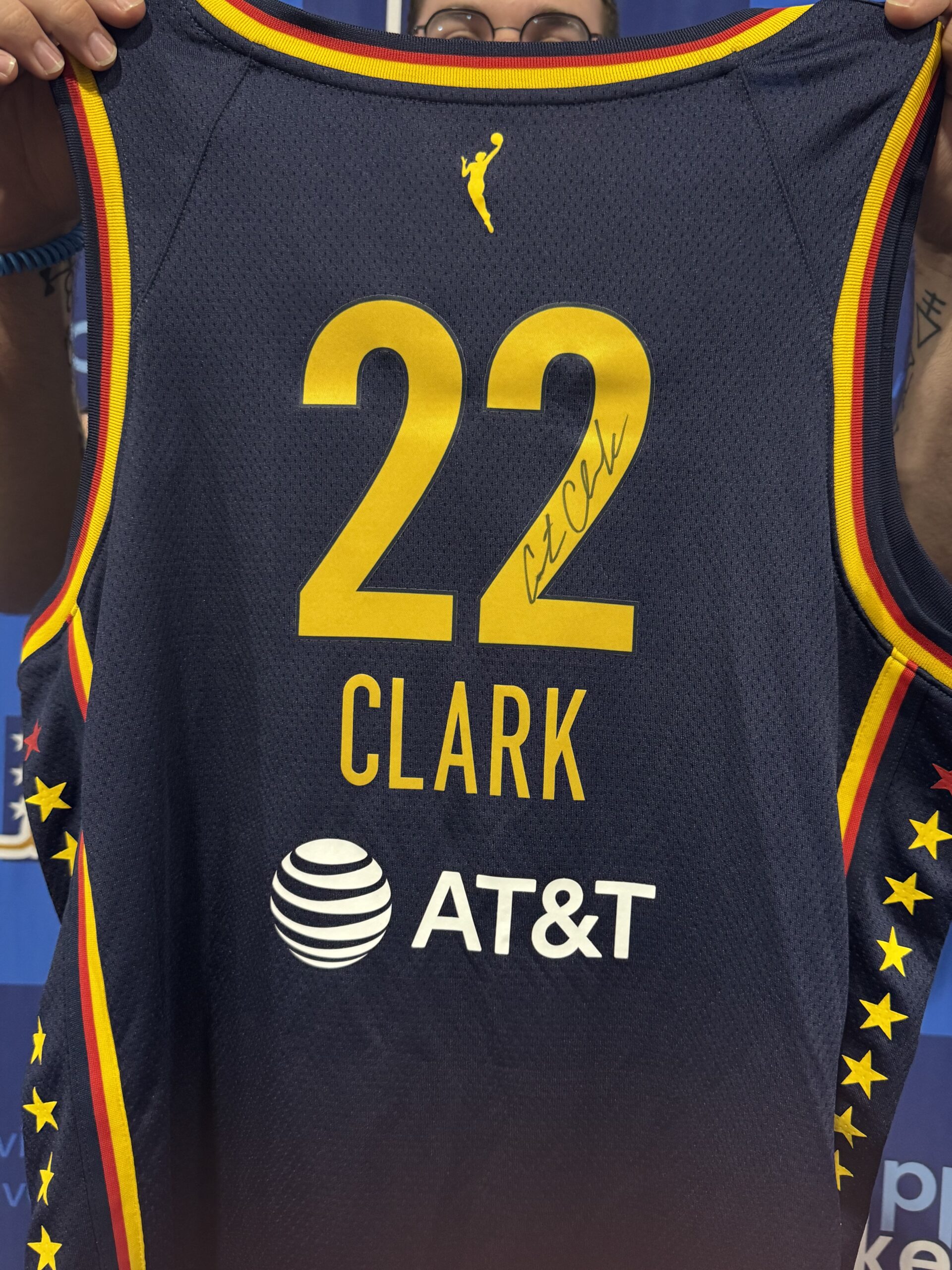 Dark blue basketball jersey with yellow number 22 and the name CLARK in bold yellow letters, trimmed in red and yellow, featuring a small yellow silhouette logo near the collar and sponsor logos at the bottom edge.